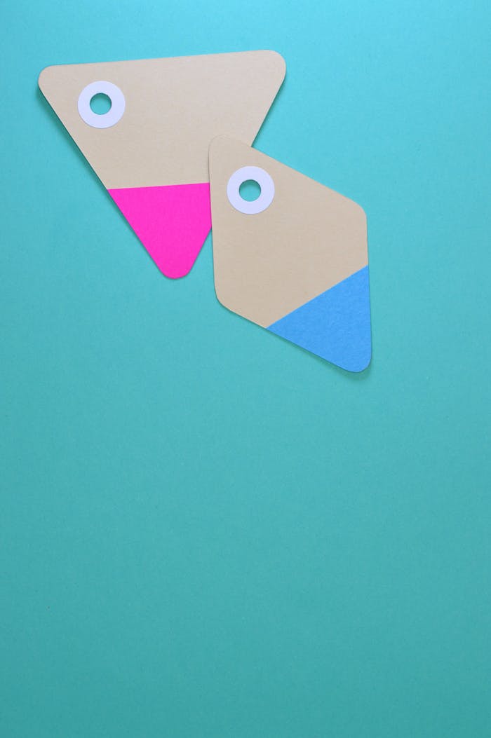 Two colorful paper tags with holes on a teal background. Ideal for design and marketing concepts.